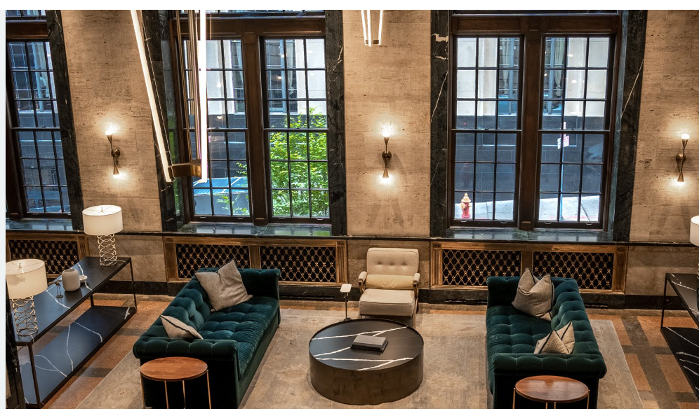 Modern hotel lobby seating with dark green sofas and warm marble finishes