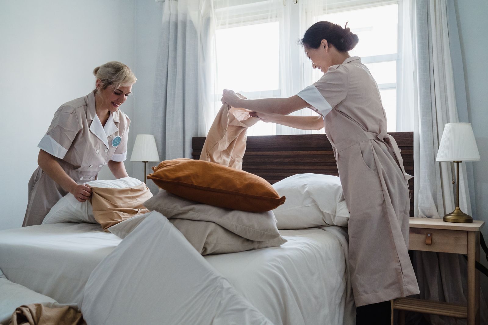 Hotel housekeepers preparing a guest room with fresh linens